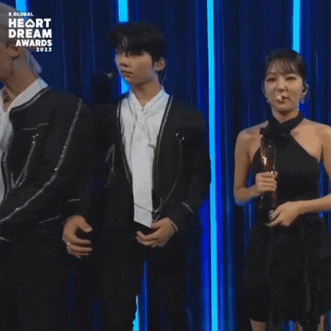 a woman in a black dress stands next to a man in a suit at a heart dream awards event .