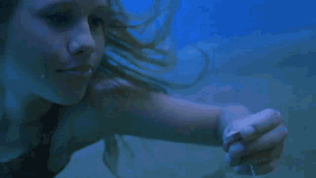a woman is swimming underwater holding a ring