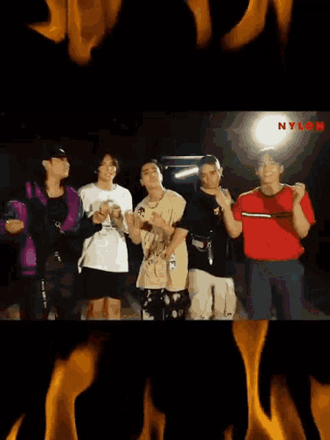 a group of young men standing next to each other in front of flames and the word nylon on the bottom