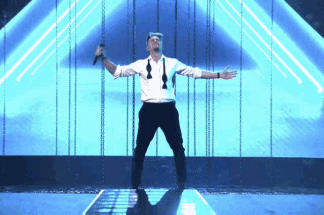 a man in a white shirt and black bow tie sings into a microphone