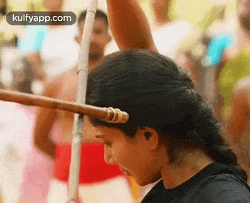 a woman is holding a wooden stick in her hair .