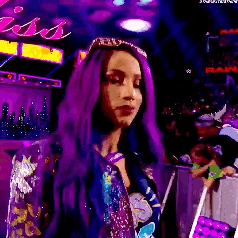 a woman with purple hair is standing in front of a crowd at a wrestling event .