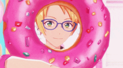 a boy with glasses is wearing a pink donut on his head .
