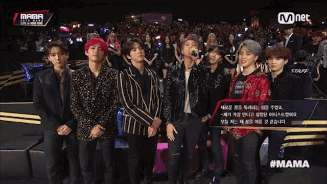 a group of young men are standing in front of a crowd at a mnet event