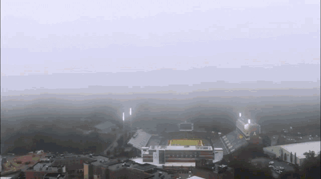 an aerial view of a foggy stadium with a yellow field