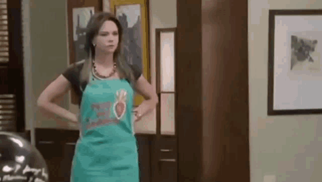 a woman in an apron is standing in a living room .
