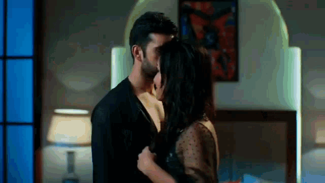 a man and woman are kissing in a bedroom in front of a mirror .