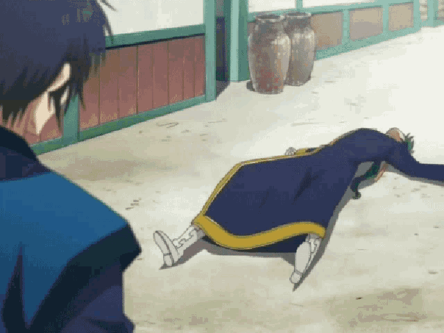 a man in a blue coat is laying on the ground looking at another man