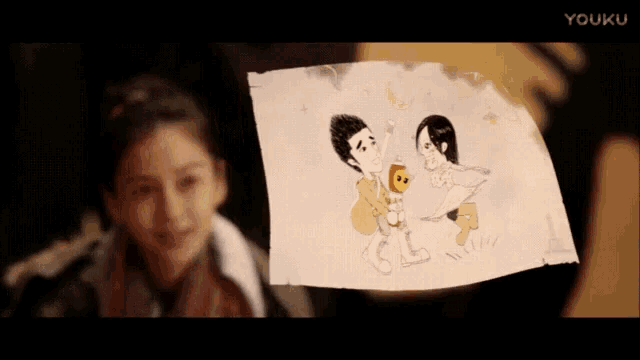 a girl is holding up a drawing of a man and woman .