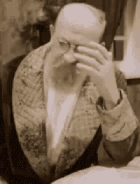 a man with a beard and glasses covering his face with his hand