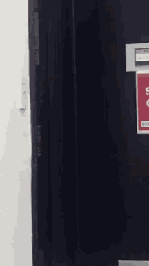 a woman is peeking out from behind a door next to a sign that says ' no smoking '