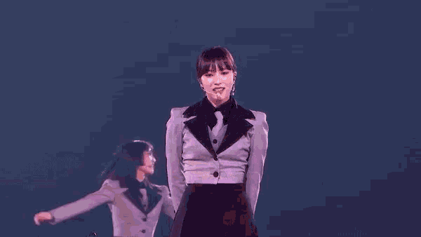 a woman in a tuxedo is standing on a stage with a microphone in her mouth
