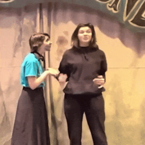 two women are standing next to each other in front of a sign that says " a "