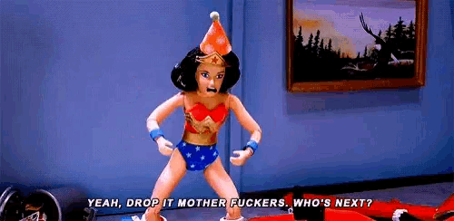 a wonder woman doll is wearing a party hat and standing in front of a picture .
