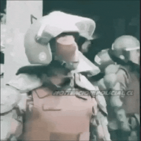 a man wearing a helmet and a bullet proof vest is standing next to another man wearing a helmet .