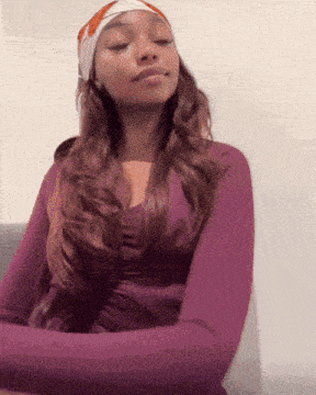 a woman with her eyes closed wearing a purple shirt