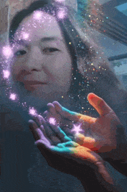 a woman is holding a rainbow in her hands with sparkles coming out of it