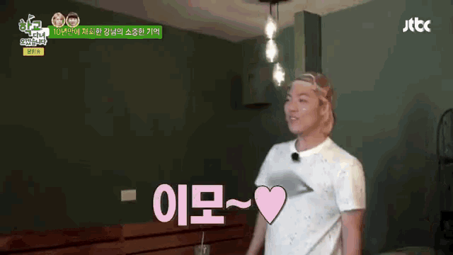 a man in a white shirt with a pink heart on his chest is standing in front of a jtbc logo