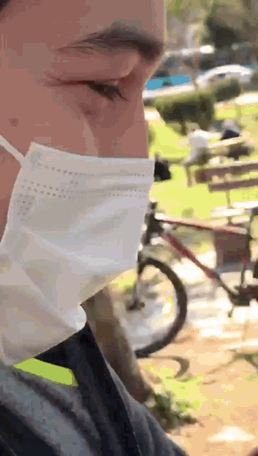 a man wearing a face mask stands in front of a bicycle