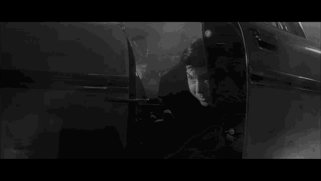 a black and white photo of a man in a car with smoke coming out of it