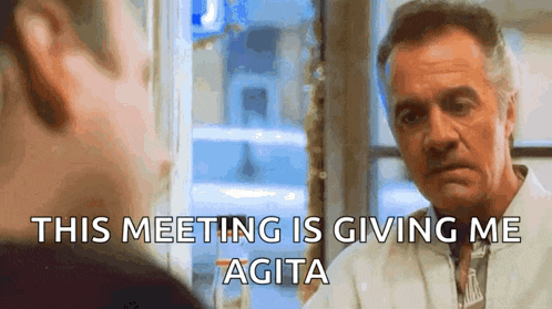 a man is talking to another man in front of a window .