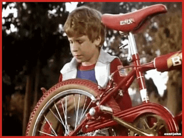 a boy on a red bmx bike with a red saddle