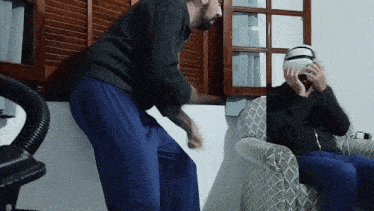 a man wearing a virtual reality headset is sitting in a chair