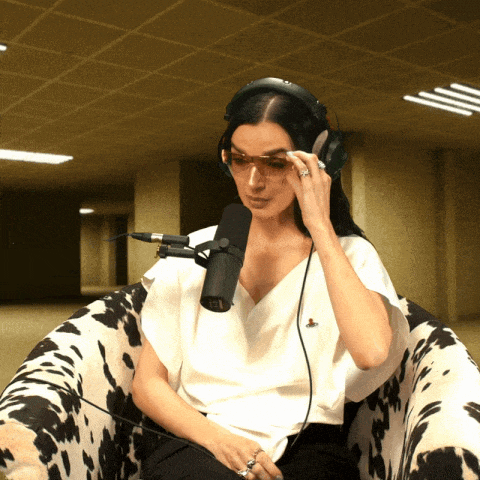 a woman wearing headphones and sunglasses is sitting in a cow print chair