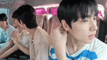 a group of young men are sitting in a van and one of them is putting a ring in his ear