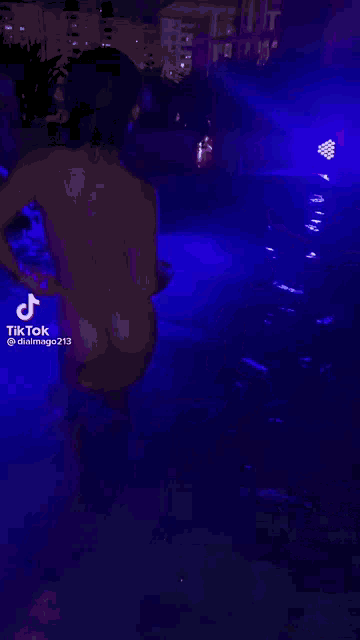 a person is swimming in a pool at night with purple lights .