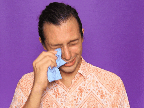 a man wipes his face with a blue cloth against a purple background