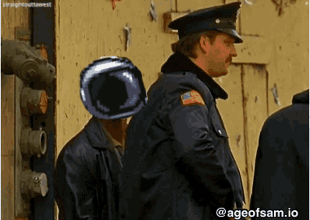 a man with a helmet on his head is standing next to a man in a leather jacket