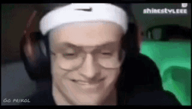 a man wearing headphones and a headband is smiling and making a funny face .