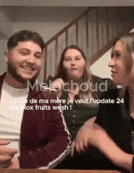 a man and two women are sitting at a table with melochoud written on the bottom right