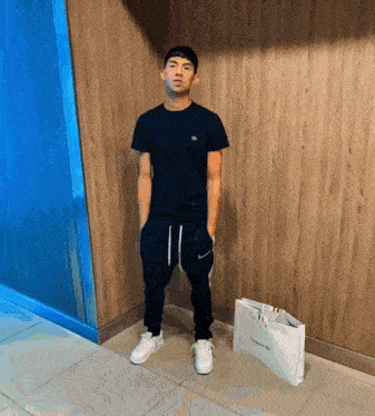 a man standing next to a white bag that says lacoste on it