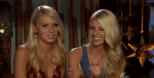 two blonde women are sitting next to each other smiling for the camera
