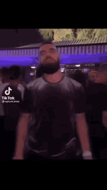a man in a black shirt is dancing in a crowd of people at a club .