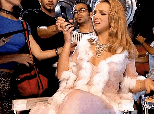 a woman in a fur coat is sitting in front of a crowd of people