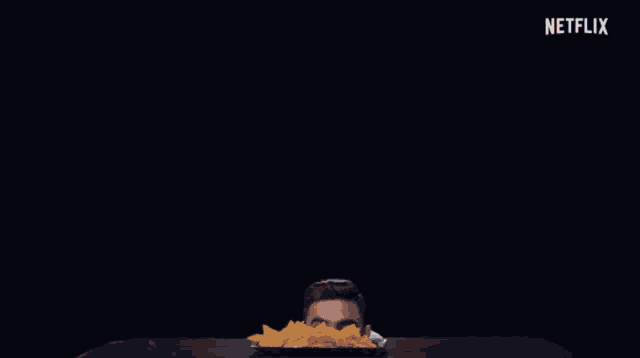 a man is sitting at a table with a tray of chips and a netflix logo in the background