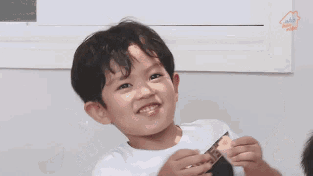 a young boy is smiling while holding a piece of paper in his hands .
