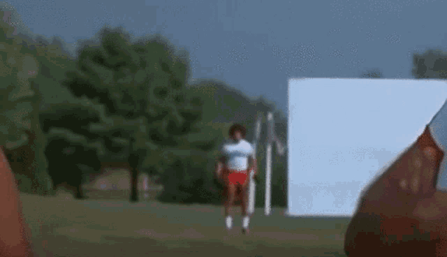 a man in a white shirt and red shorts is running in a park .