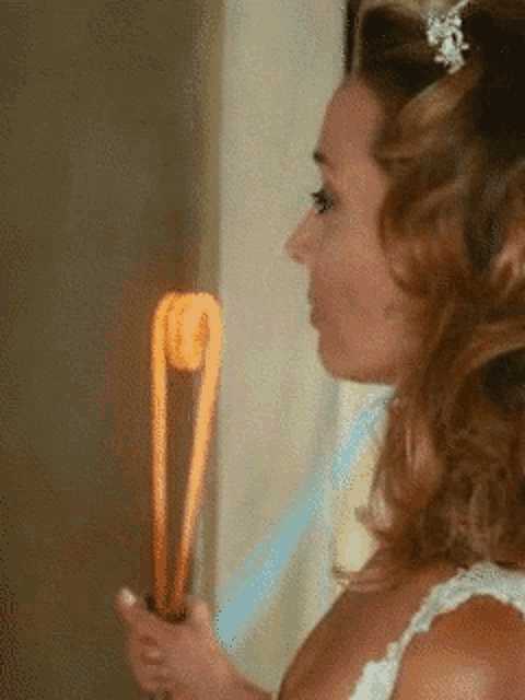 a woman in a wedding dress is holding a candy cane in her hand
