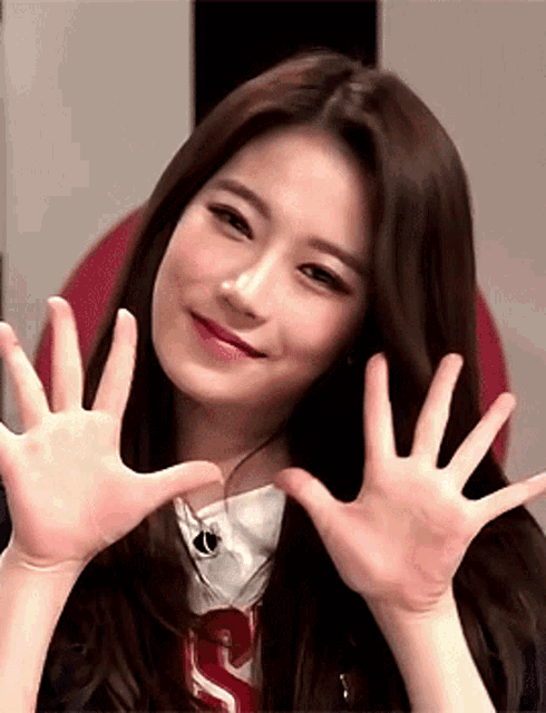 a woman making a heart with her hands and wearing a shirt with the letter s on it