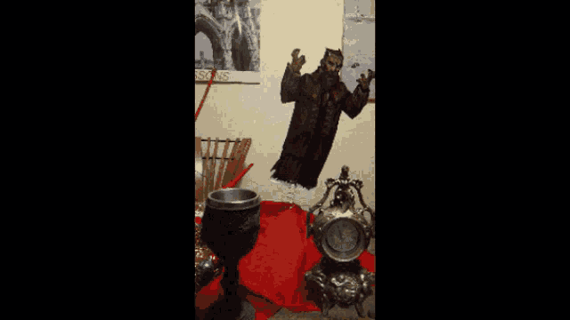 a clock and a goblet are on a table in front of a painting of a man