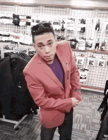 a man in a red suit jacket is standing in a clothing store .