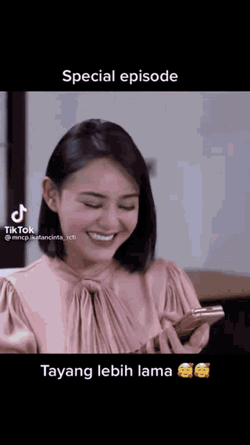 a woman in a pink shirt is smiling while looking at her phone