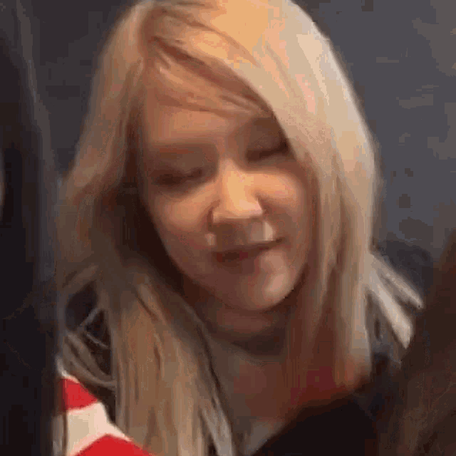a close up of a woman 's face with blonde hair and a black shirt .