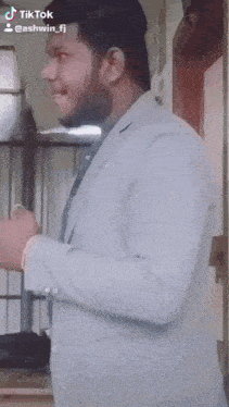 a man in a suit is standing in front of a door and has a tiktok account