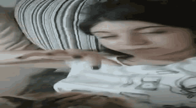 a woman is laying on a bed playing with a cat .