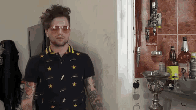 a man wearing sunglasses is standing in front of a wall with a sign that says cocktail